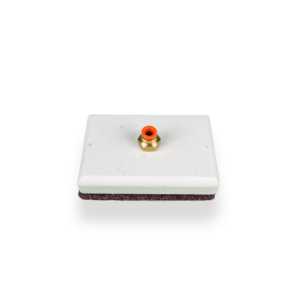 Close-up of a small orange knob on a brass fitting mounted on a pale rectangular surface.