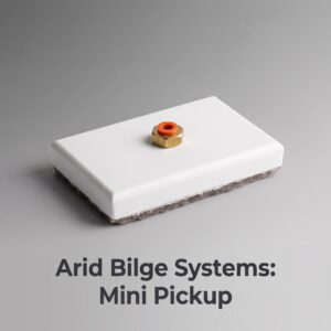 Close-up of a small wooden block with an orange O-ring resting on a white pedestal, against a gray background; partial text 'Mini Pickup' visible nearby.