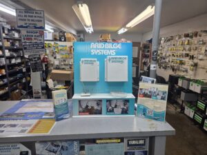 Blue Arid Bilge Systems display at a marine store with shelves of accessories and signs around it.