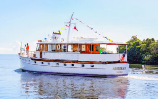 Aurora II cruising with signal flags above the wooden cabin.