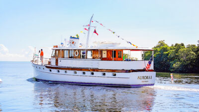Aurora II cruising with signal flags above the wooden cabin.