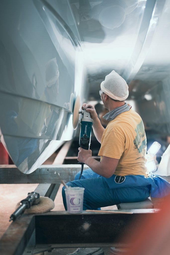 A Twin Vee craftsman polishing a boat hull in the factory.