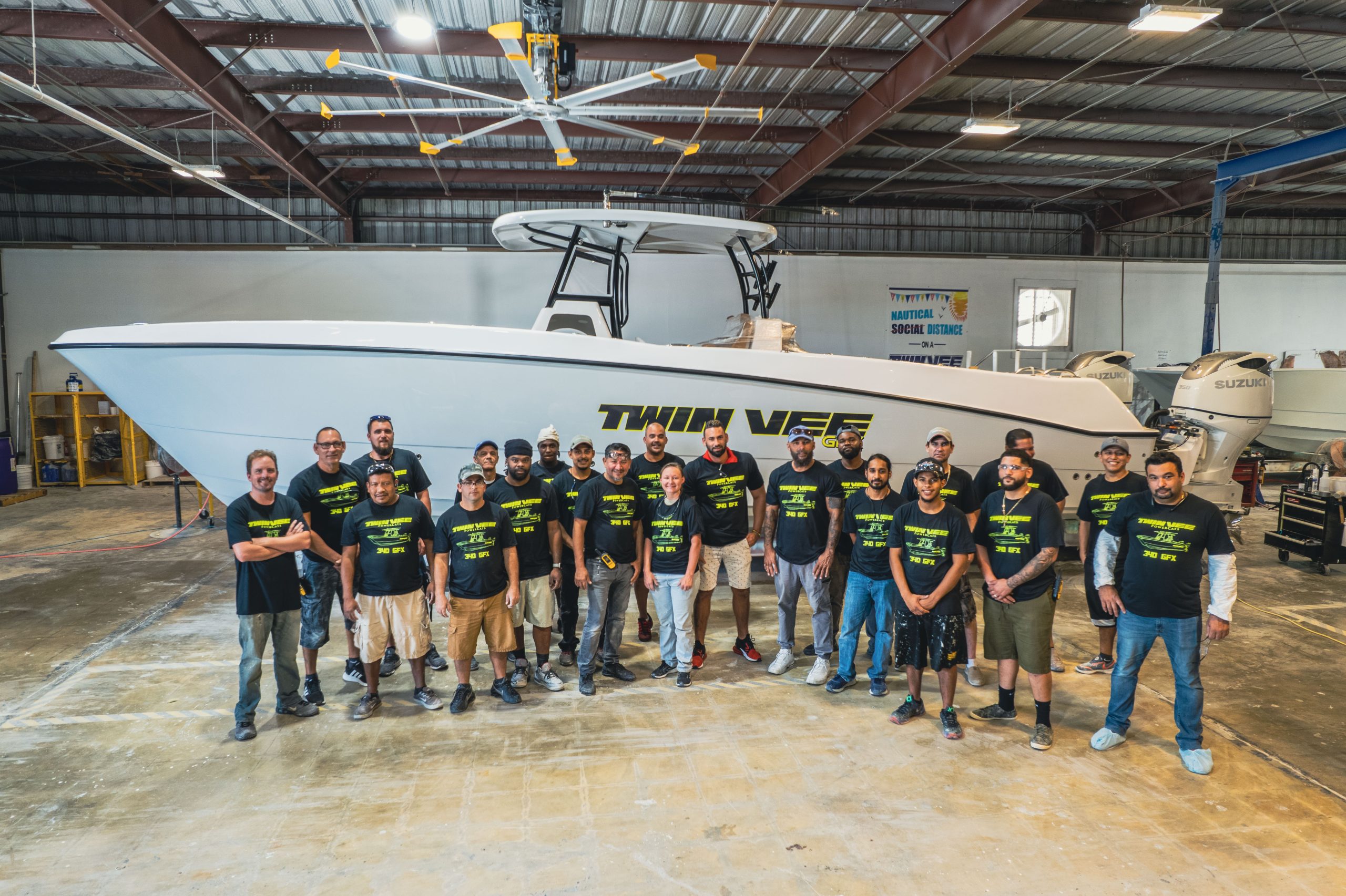 Twin Vee team gathered beside a power catamaran inside the factory.
