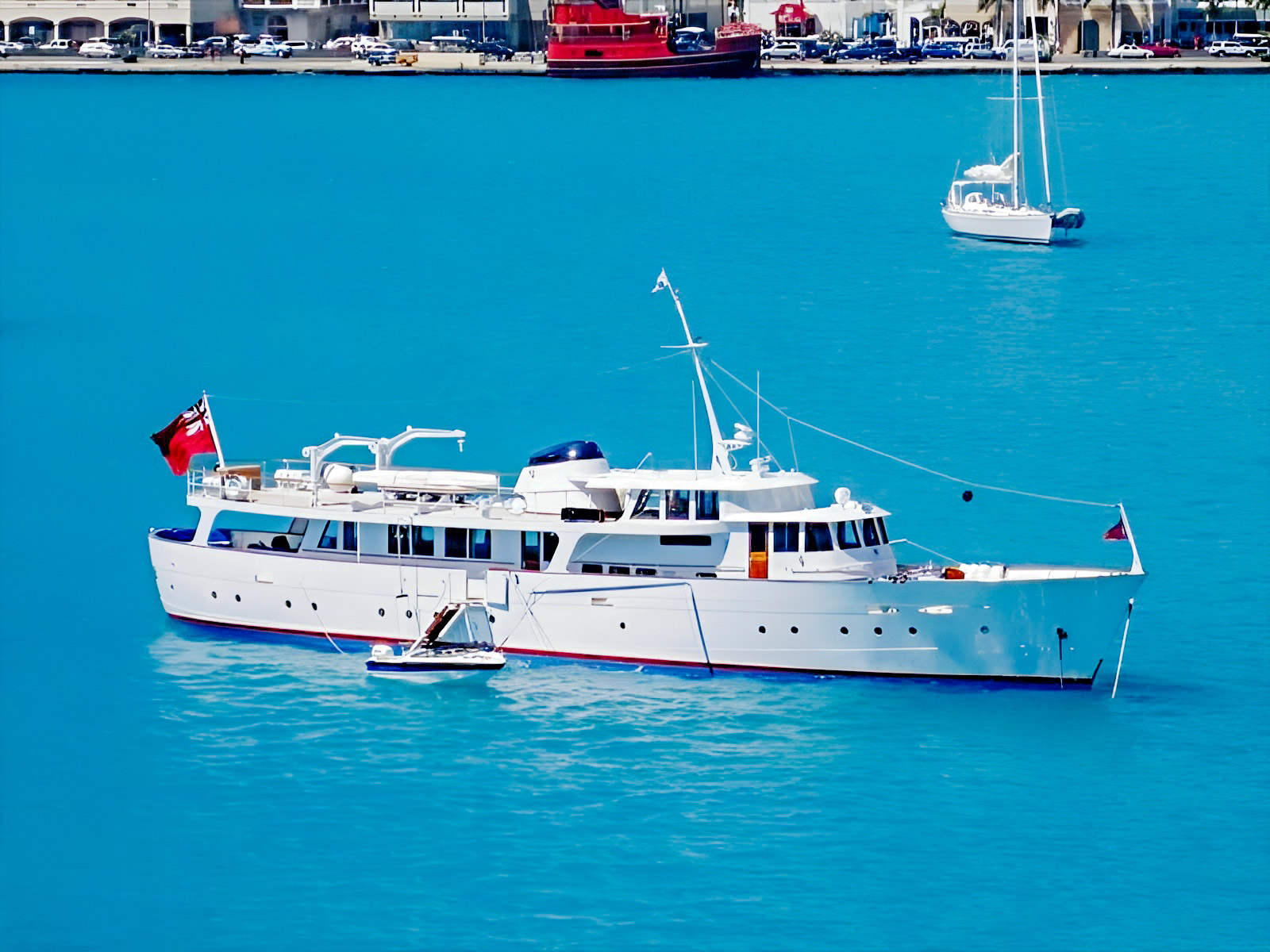 Blue Guitar, the classic white motor yacht, at anchor in turquoise water.