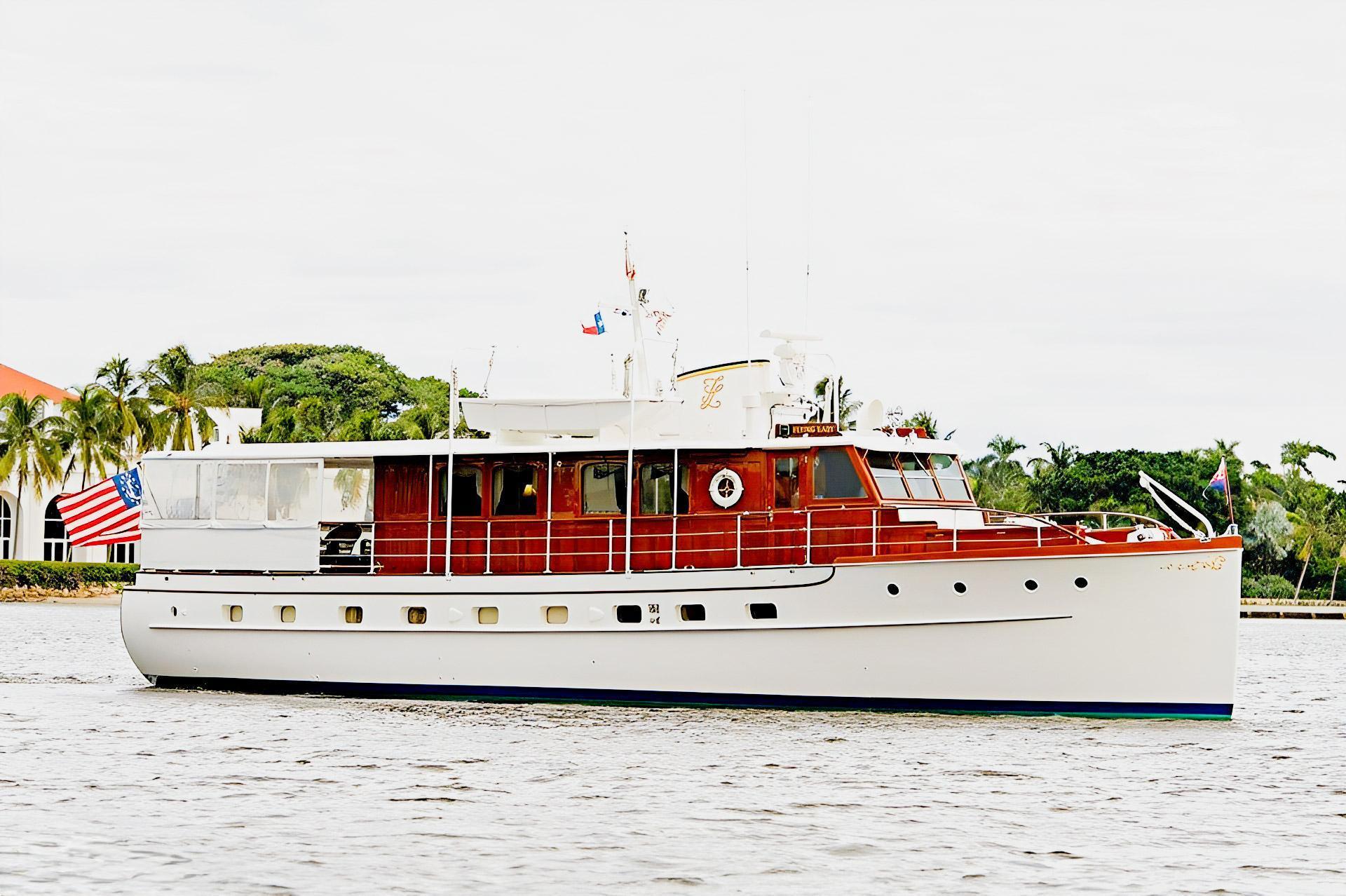 flying-lady-original-exterior - Arid Bilge Systems Flying Lady with white hull and varnished wooden cabin, photographed broadside on the water.