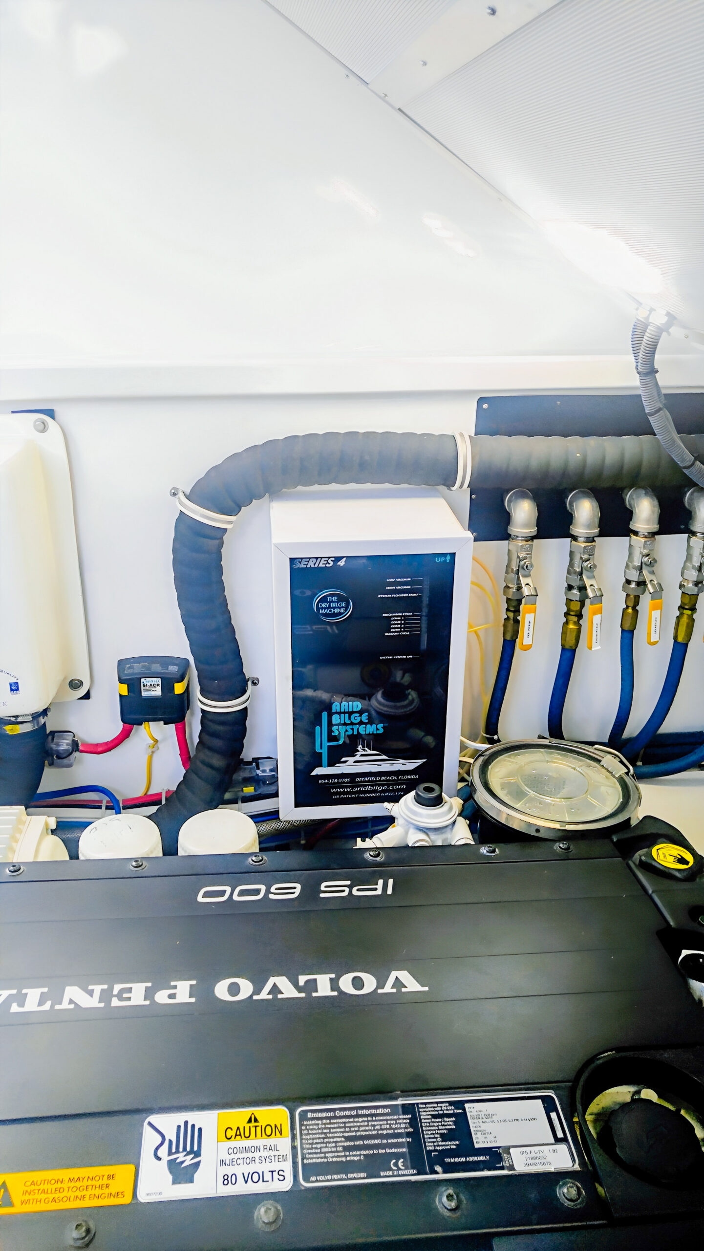 Arid Series 4 cabinet beside blue hoses and yellow-handled valves, with Volvo Penta machinery in the foreground.